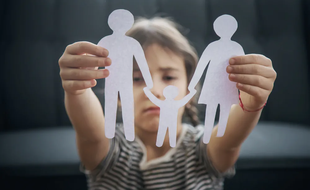 Child holding paper cutout figures representing a family, illustrating family relationships and legal matters involving children.